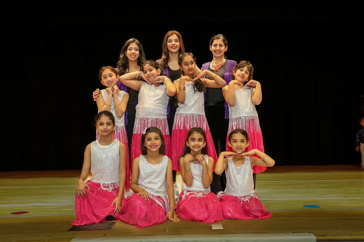 Dance recital cast and instructors photographed on stage